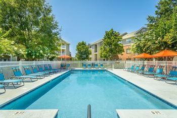 a swimming pool with blue chairs and orange umbrellas